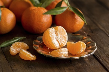 Fresh Tangerines with green leaves on a wooden background